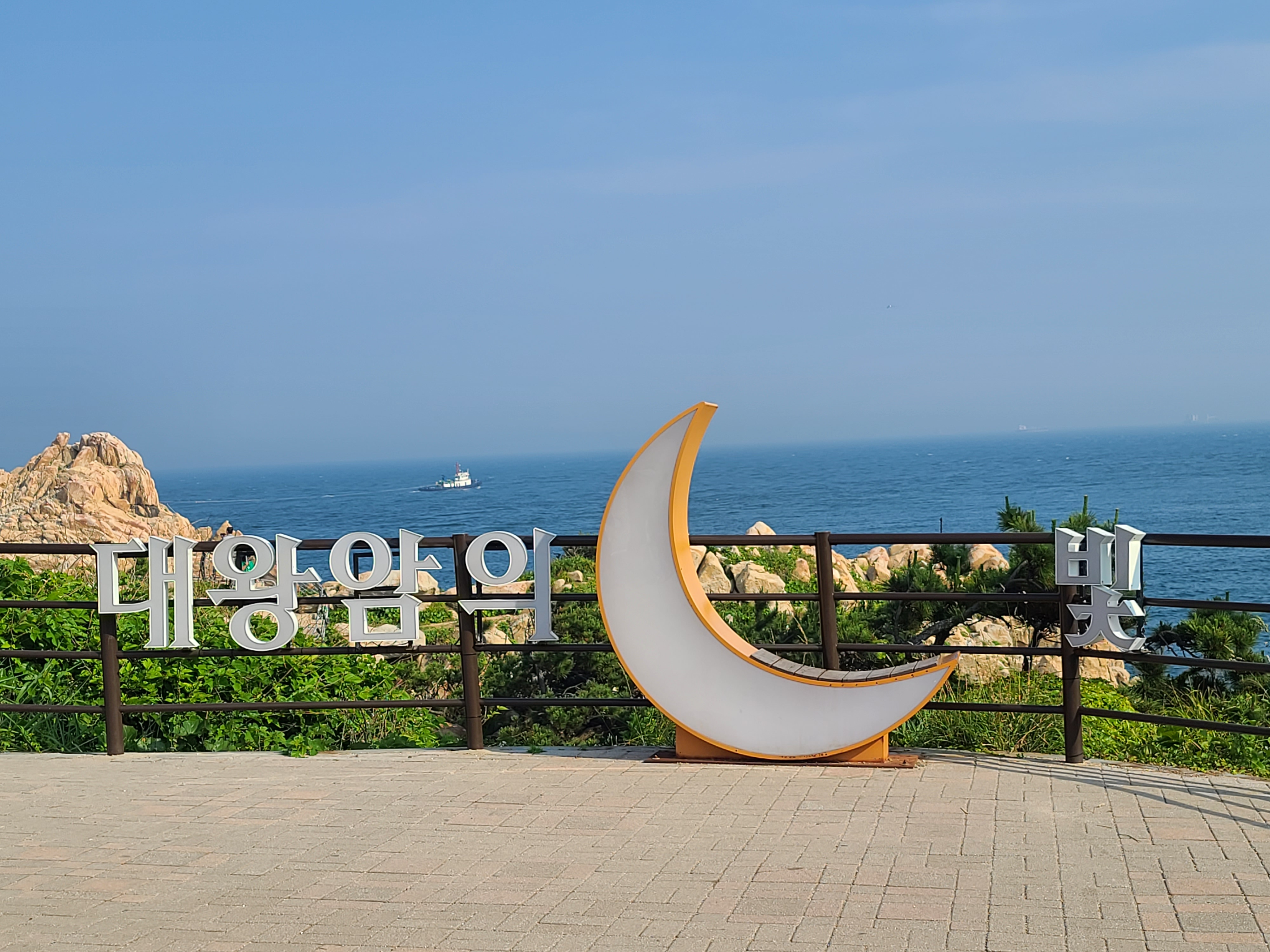 따뜻한 톤의 해안 보도, 공공 공간이 바다에 부드럽게 안긴 모습.